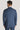 Man wearing mid blue melange double-breasted suit jacket and trousers, shown from back view with white shirt collar visible.
