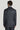 Man wearing dark blue plaid suit jacket with brown windowpane pattern and gray dress shirt, shown from back view.