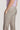 Ecru flat-front trousers with button closure and side pockets on a man wearing a purple shirt.