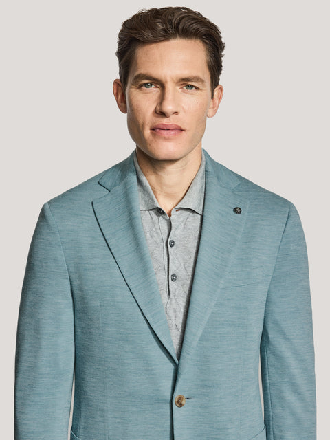 Man wearing a soft teal melange blazer with a notched lapel and button front over a gray shirt.