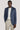 Man wearing denim blue melange blazer over white t-shirt and cream trousers.