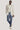 Man wearing cream solid blazer with notch lapels and button closure over white shirt, paired with blue denim jeans.