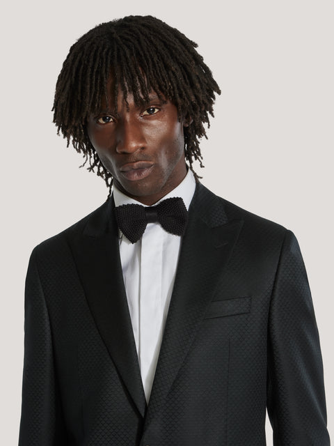 Black dinner jacket with textured weave pattern, notch lapels, and single button closure, styled with white dress shirt and b