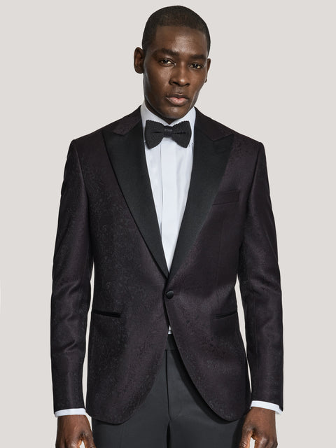 Burgundy paisley dinner jacket with notch lapels worn with white dress shirt and black bow tie.